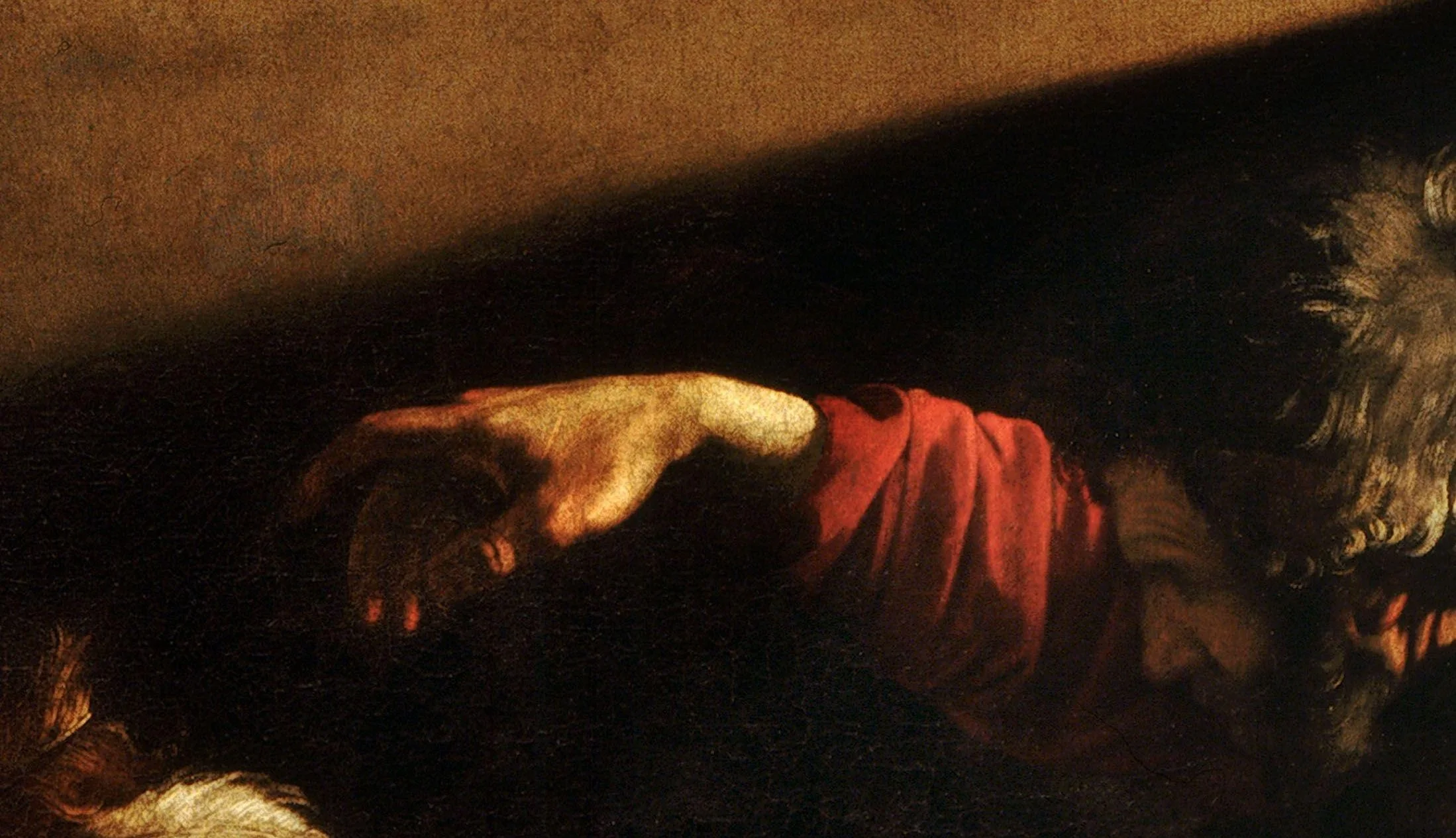 Detail of The Calling of Saint Matthew: the pointing hand is a few strokes of warm light along the knuckles and almost nothing in the shadow, with the edge of the beam cutting the wall above it. The hand is not drawn and filled in, it is found where the light stops.
