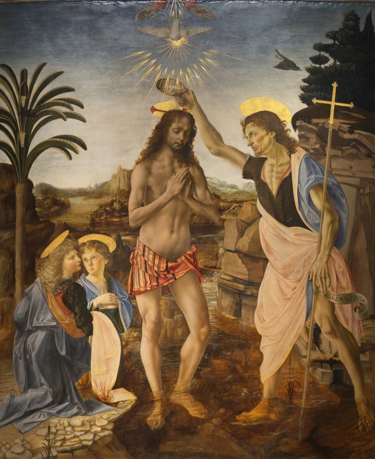 The Baptism of Christ, made in Verrocchio's shop with master and apprentices working on one panel. The kneeling angel at the far left holding the robes is the part Vasari gives to the young Leonardo, and Vasari adds the story that Verrocchio never touched color again after seeing it.