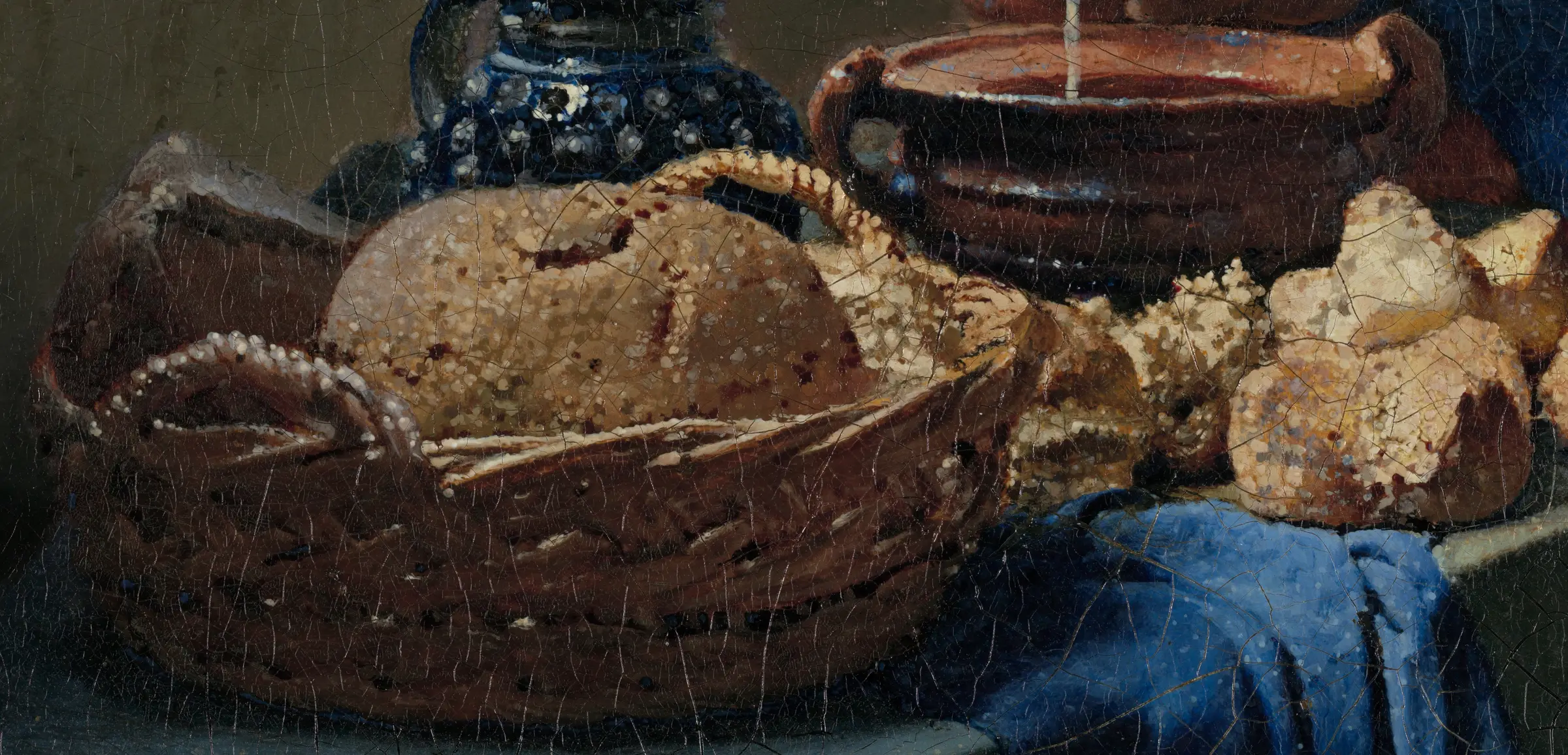Detail of the bread in The Milkmaid: the crust is built from small round beads of pale paint sitting on top of the dried colour under them, some on the loaf, some on the wicker, some out on the rim of the basket where there is no bread at all. Close up they are dots. From across a room they are crumbs catching the window.